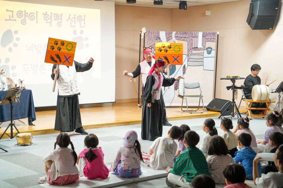 무대 배경에 고양이 혁명 선언 애니메이션이 펼쳐진 어린이 마당놀이 공연 장면