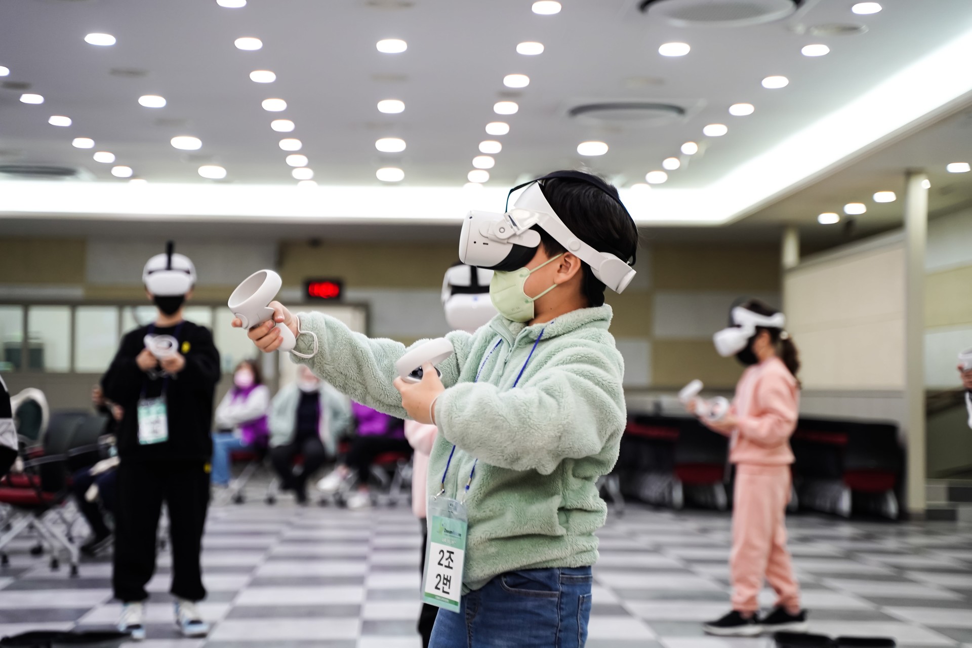 현대적 VR 헤드셋을 쓰고 컨트롤러로 가상세계에 손을 뻗는 참여자
