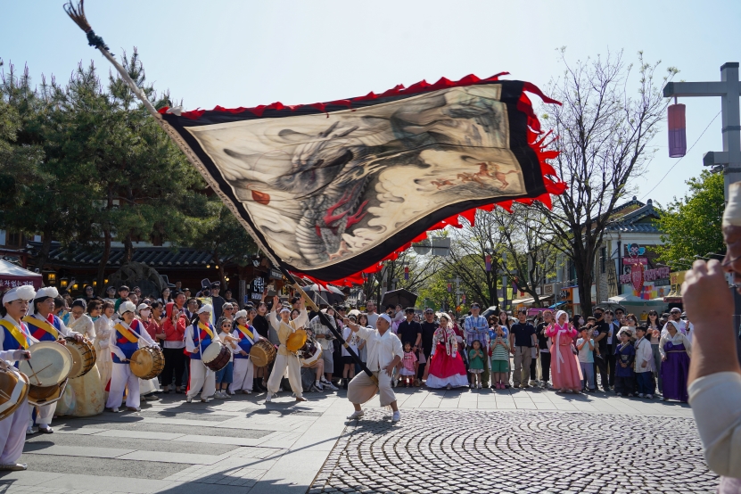 전주한옥마을 전통연희 퍼레이드에서 거대한 용깃발을 휘날리는 기수와 풍물패, 관람객들의 모습