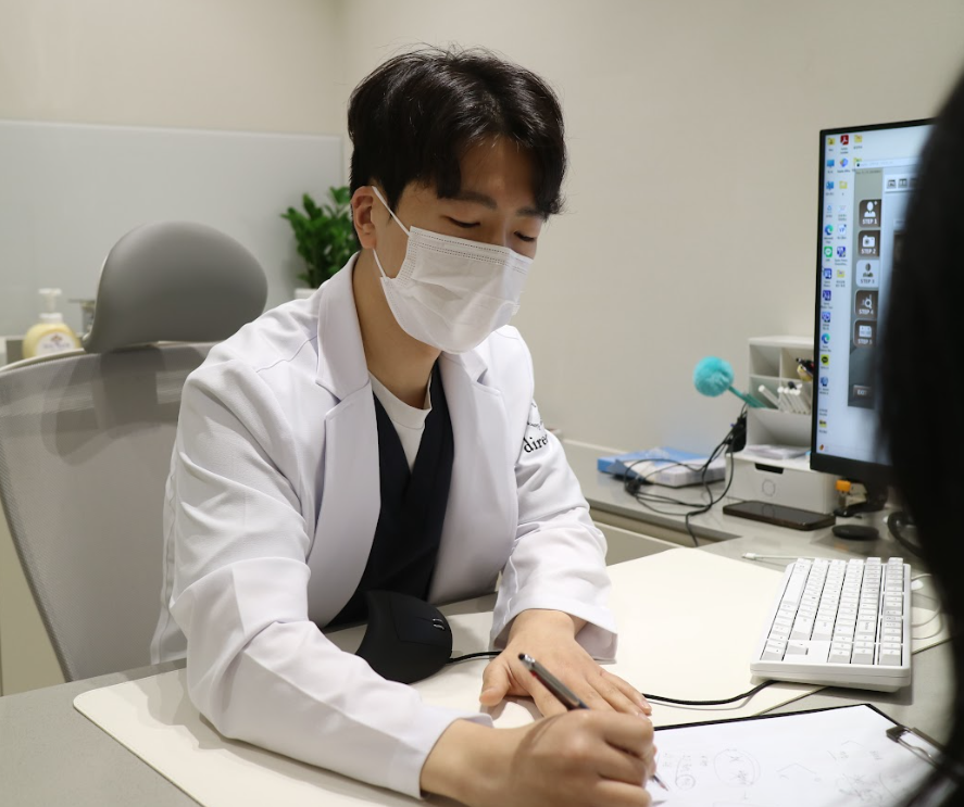사마귀 제거 치료 계획을 차트에 직접 작성하며 환자에게 설명하는 원장 진료 사진