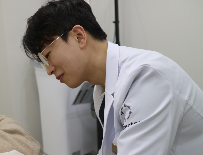 사마귀 제거 시술을 위해 확대경을 착용하고 병변 부위를 정밀 관찰하는 원장 시술 사진