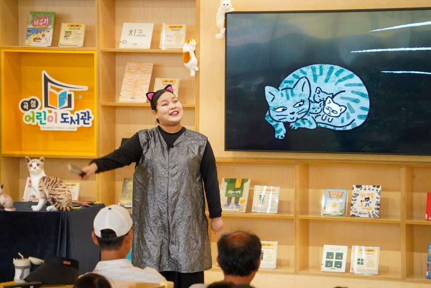 엄마 품에 안긴 아기고양이 애니메이션 스크린 앞에서 무명이 역 배우가 연기하는 모습