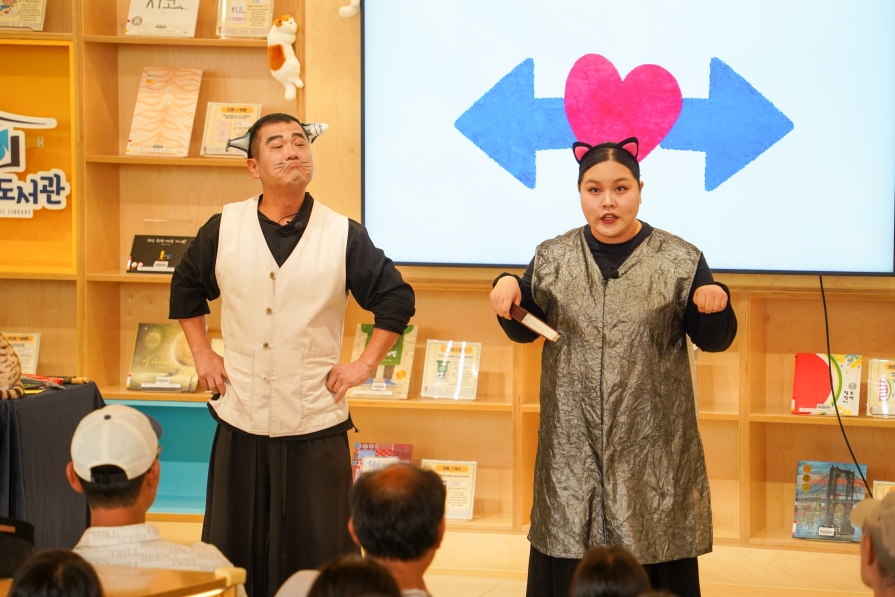 꽁치 인형을 머리에 쓴 배우와 고양이 무명이가 하트와 화살표 화면 앞에서 친구가 되는 비법을 이야기하는 장면