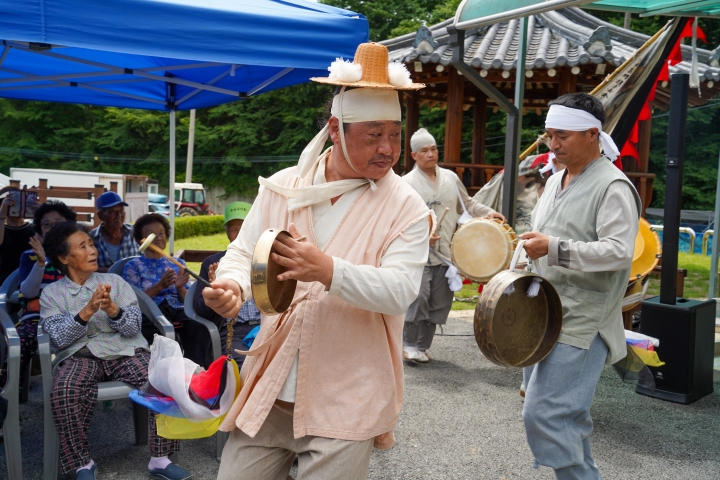 무주 치목마을회관 앞에서 꽹과리와 징을 연주하며 지신밟기를 펼치는 복이팡팡 공연단과 박수 치는 마을 어르신들