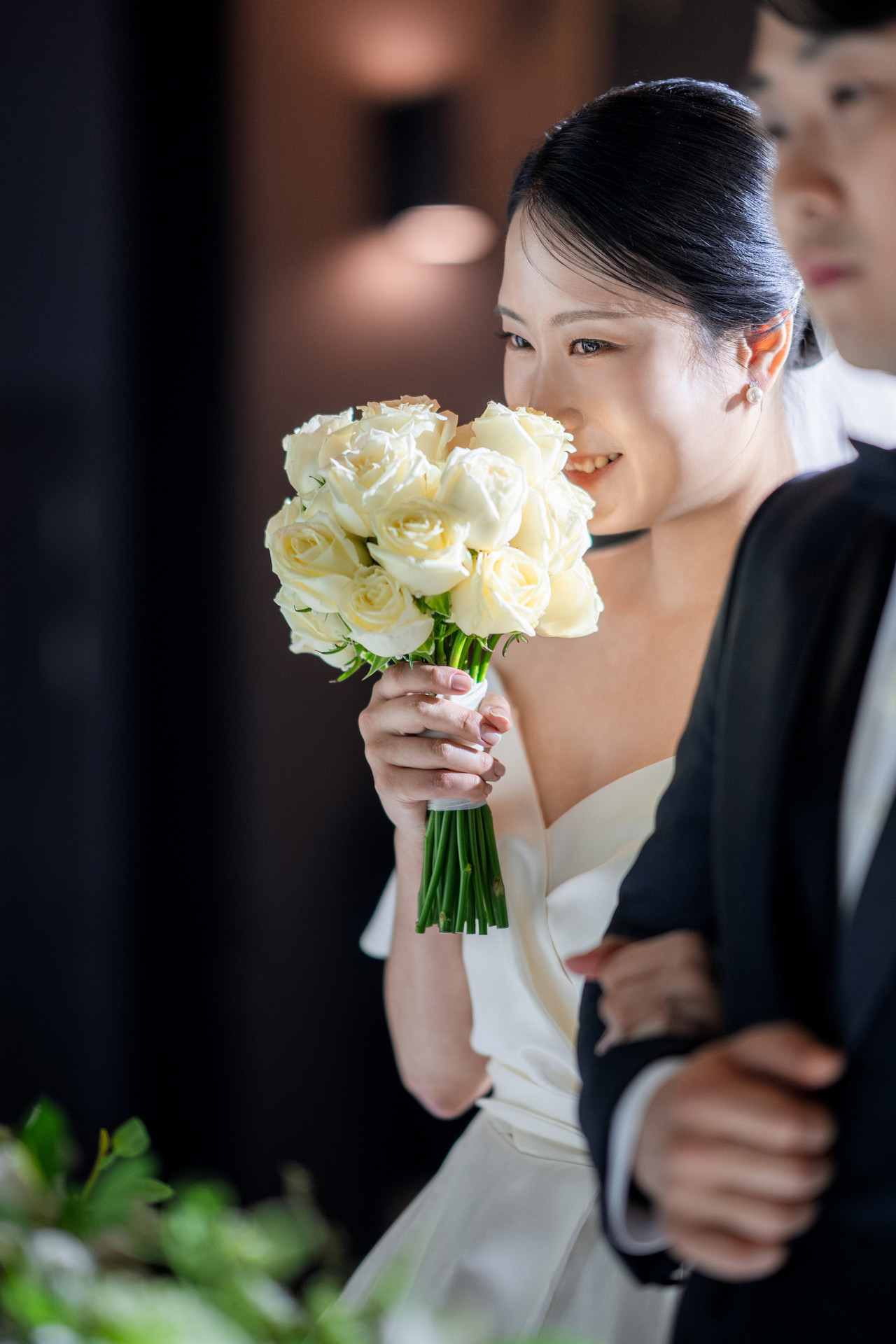 흰 장미 부케를 들고 팔짱을 낀 신부