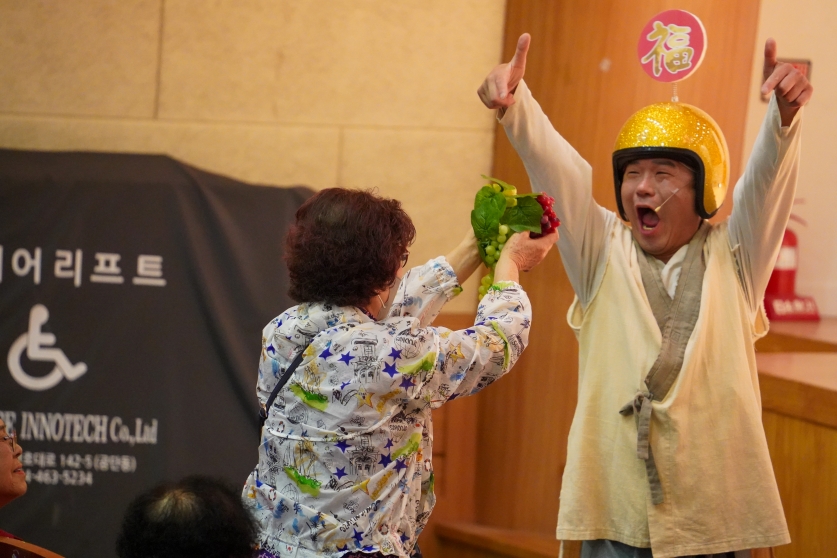 복배달부가 어르신에게 포도송이를 전하며 자손복을 기원하는 모습