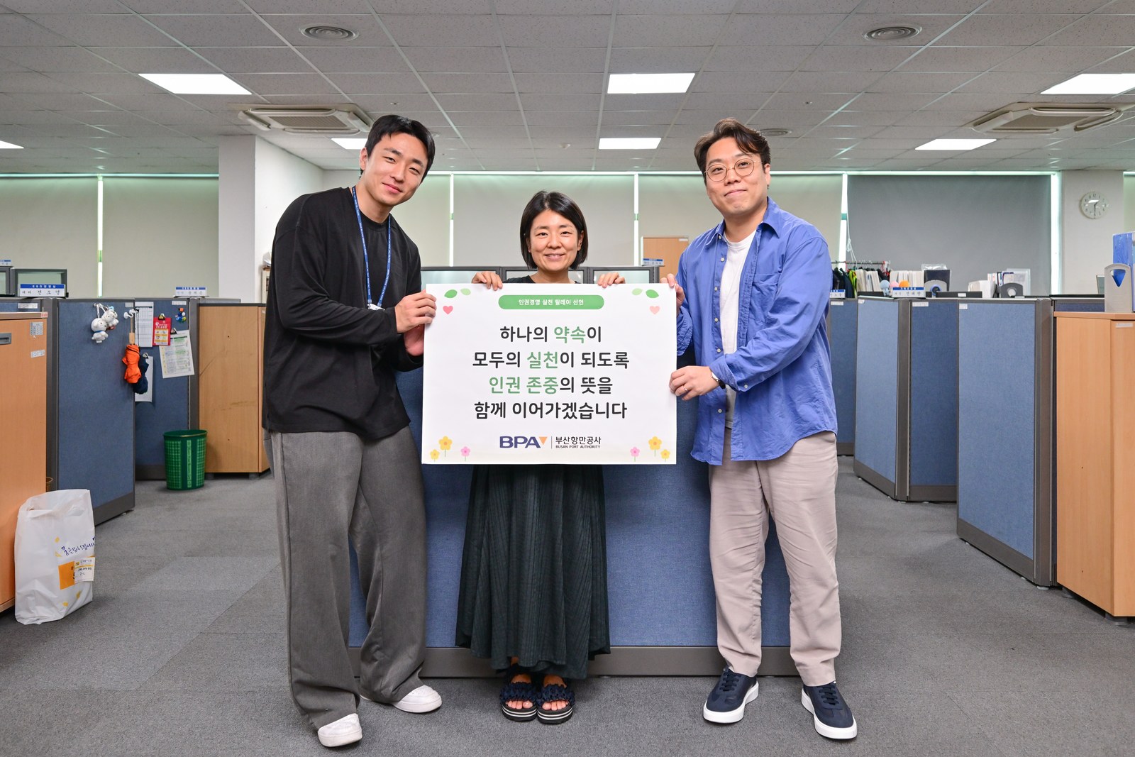 준법경영TF팀 직원 세 명이 인권 존중 약속 피켓을 함께 들고 사무실에서 촬영한 모습