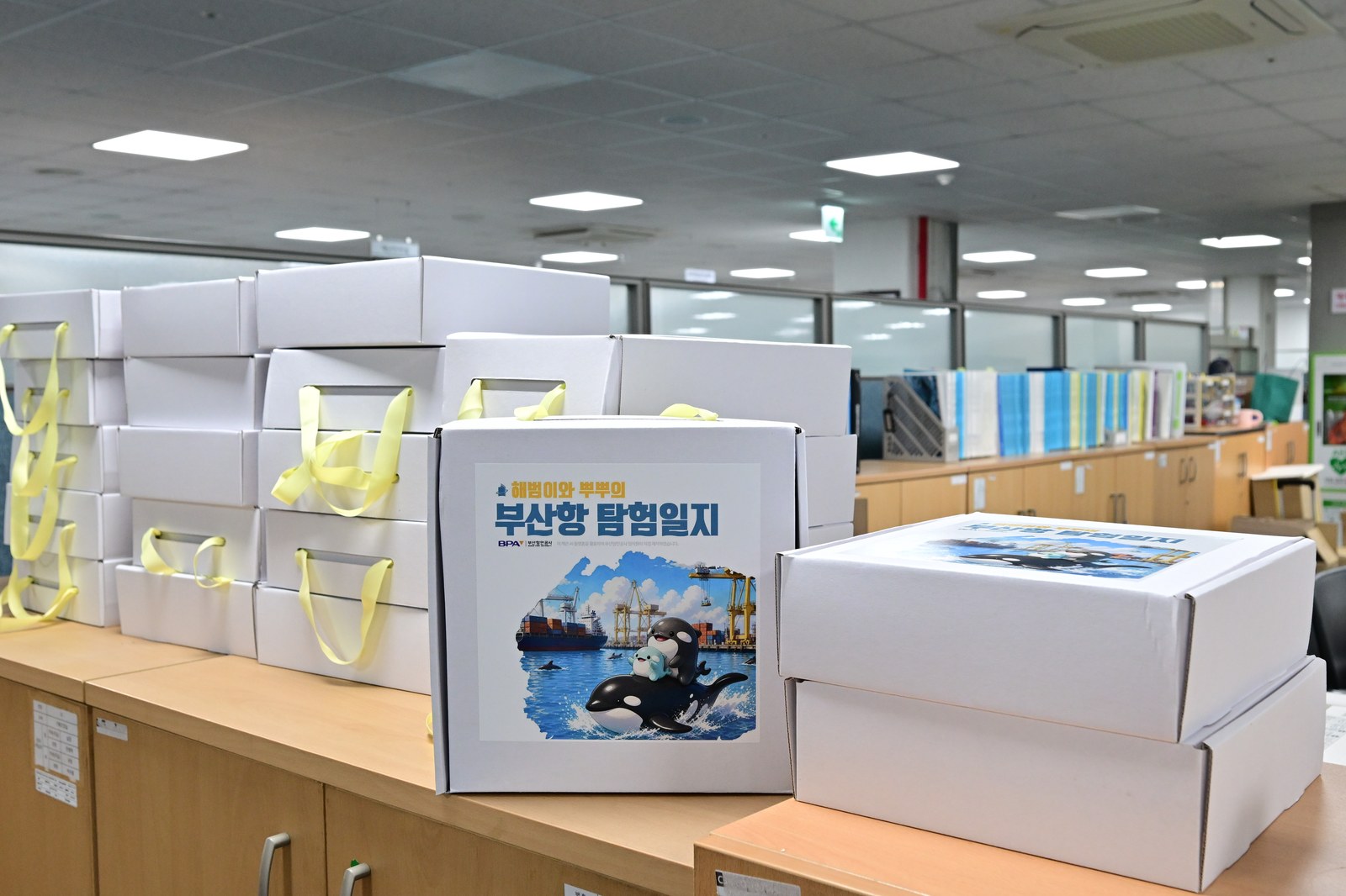 노란 리본으로 묶은 '부산항 탐험일지' 포장 상자가 사무실 수납장 위에 줄지어 놓여 있는 모습
