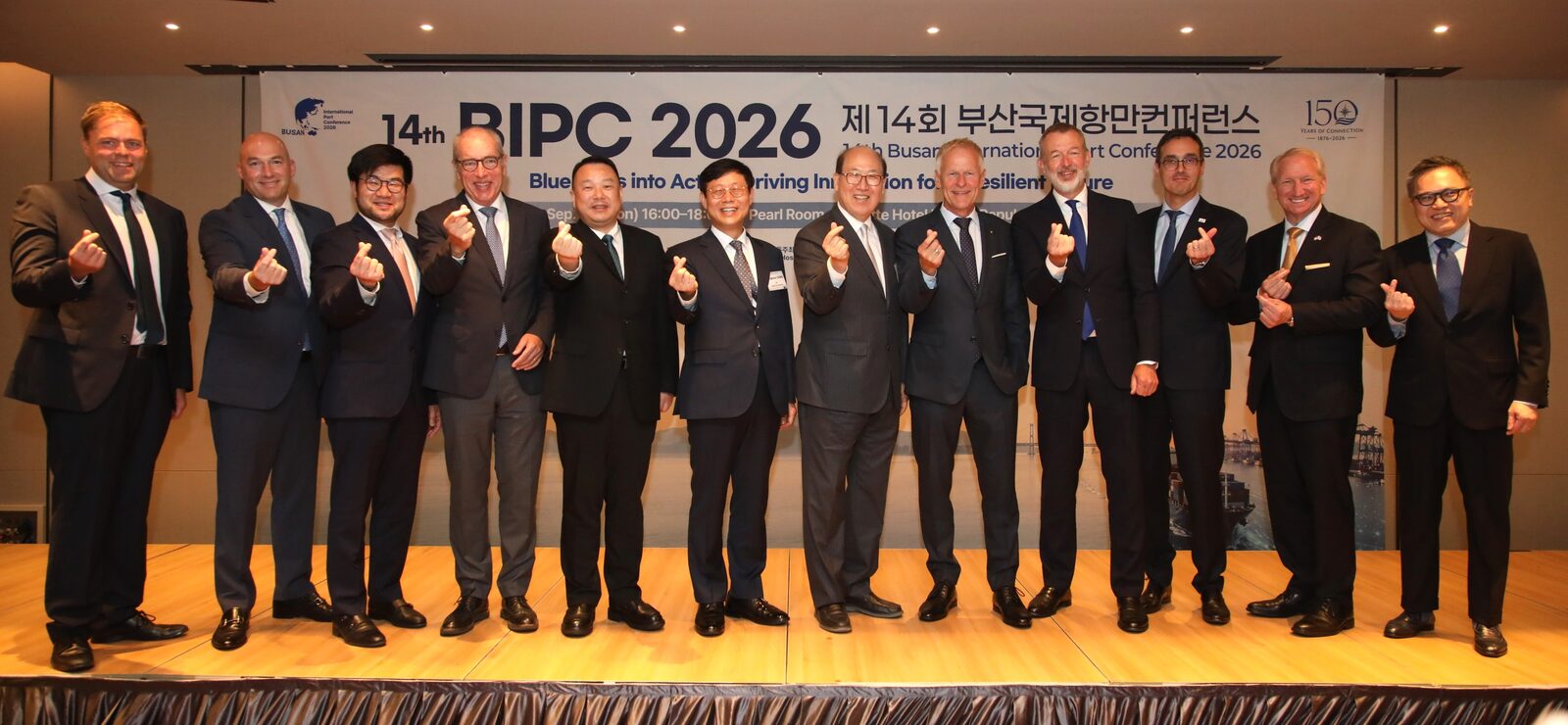 제14회 부산국제항만컨퍼런스 배너 앞 단상에 세계 주요 항만 대표 열두 명이 나란히 서서 기념 촬영을 하는 모습