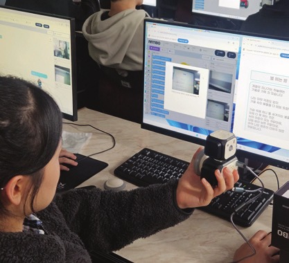 아티보를 들고 화면으로 AI 코딩을 하는 학생