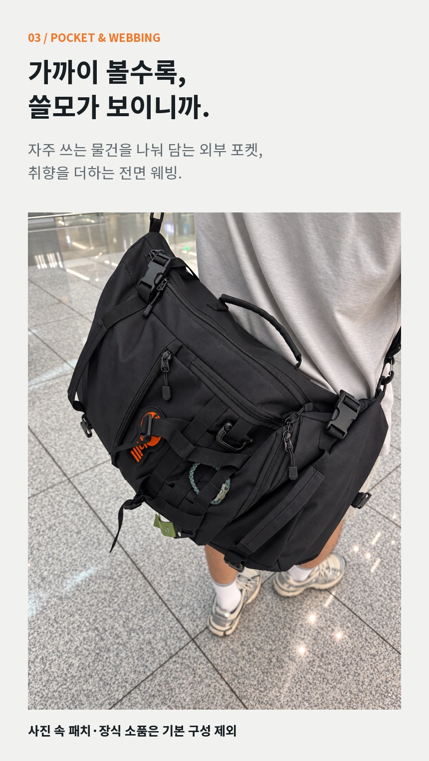 착용 중인 후크건의 외부 포켓, 지퍼, 버클과 전면 웨빙을 가까이 보여주는 이미지. 사진 속 패치와 장식 소품은 기본 구성 제외.
