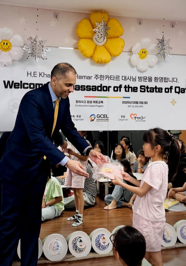 소망하던 선물을 받은 선덕원 아동이 주한 카타르 대사로부터 선물을 받으며 감사 인사를 전하고 있다.