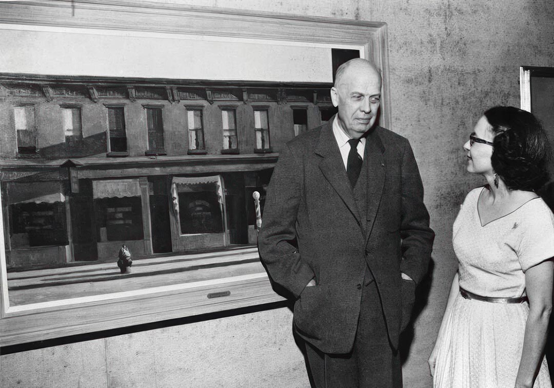 Hopper at the Virginia Museum of Fine Arts in 1953 with Bell Worsham, next to his painting Early Sunday Morning (1930). Virginia Museum of Fine Arts, Richmond, Photo Archives, © Virginia Museum of Fine Arts.