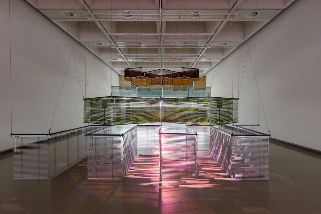 Haegue Yang, Star-Crossed Rendezvous after Yun, 2024, aluminum venetian blinds, powder-coated aluminum hanging structure, steel wire rope, moving spotlights, DMX controller, speaker, tripod. Courtesy of the artist. Installation view of Leap Year, Hayward Gallery, London, United Kingdom, 2024. Photo by Mark Blower.