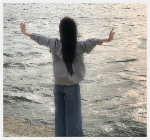 바닷가 앞에서 양팔을 벌려 힐링하는 모습