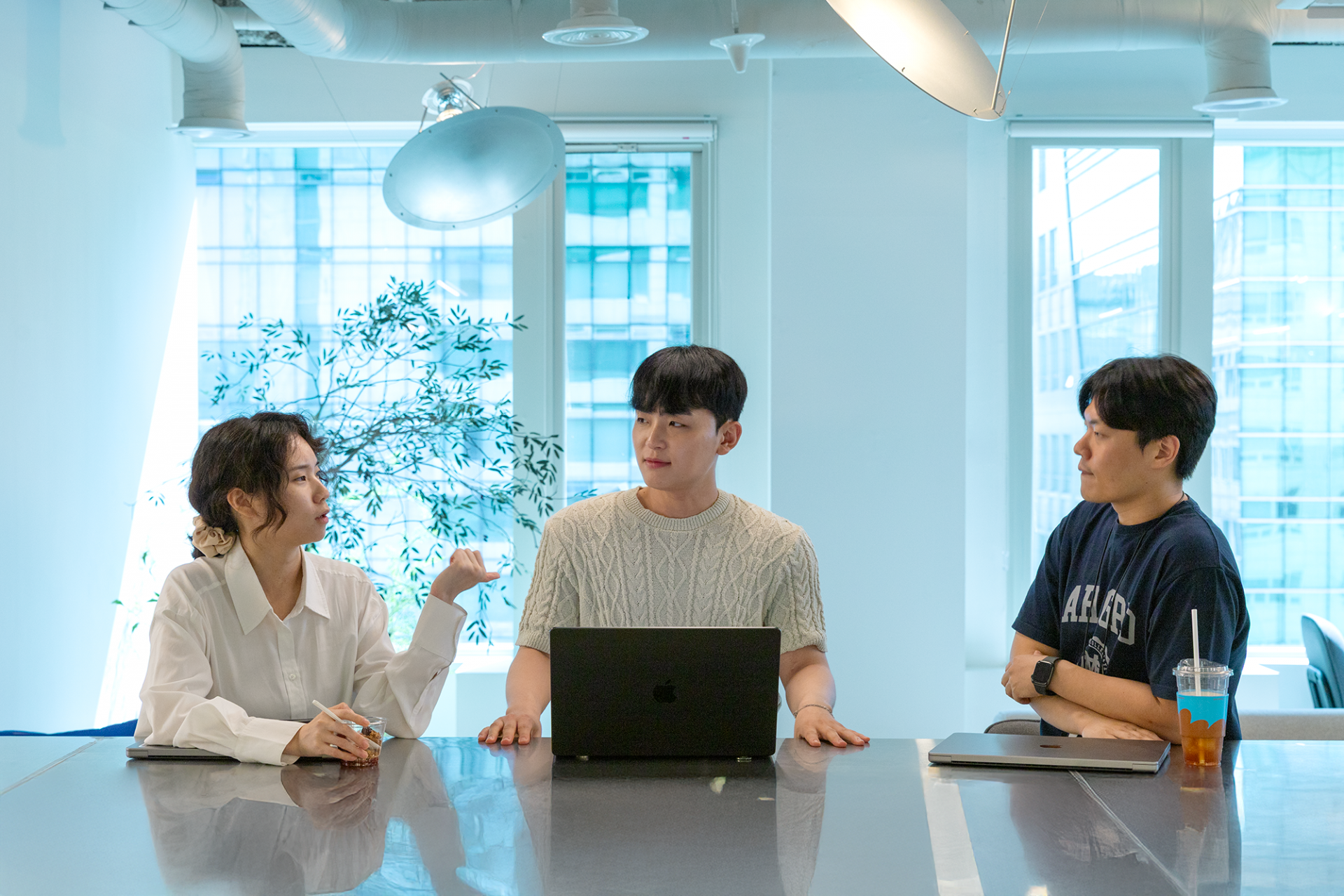 아임웹 데이터팀. 세 명의 팀원이 스탠드 테이블에서 이야기를 나누고 있는 모습.