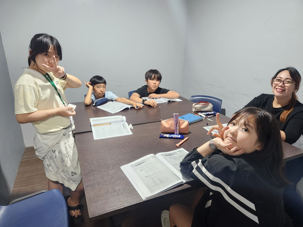 교재를 펼치고 한 테이블에 둘러앉은 학생들