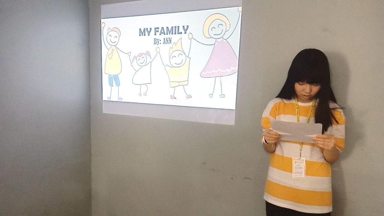 가족을 소개하는 화면 앞에서 발표 자료를 읽는 학생