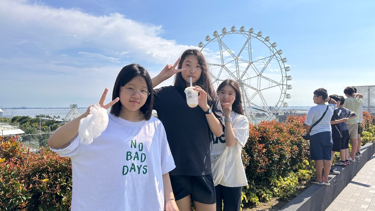 관람차 앞에서 음료를 들고 함께 서 있는 학생들
