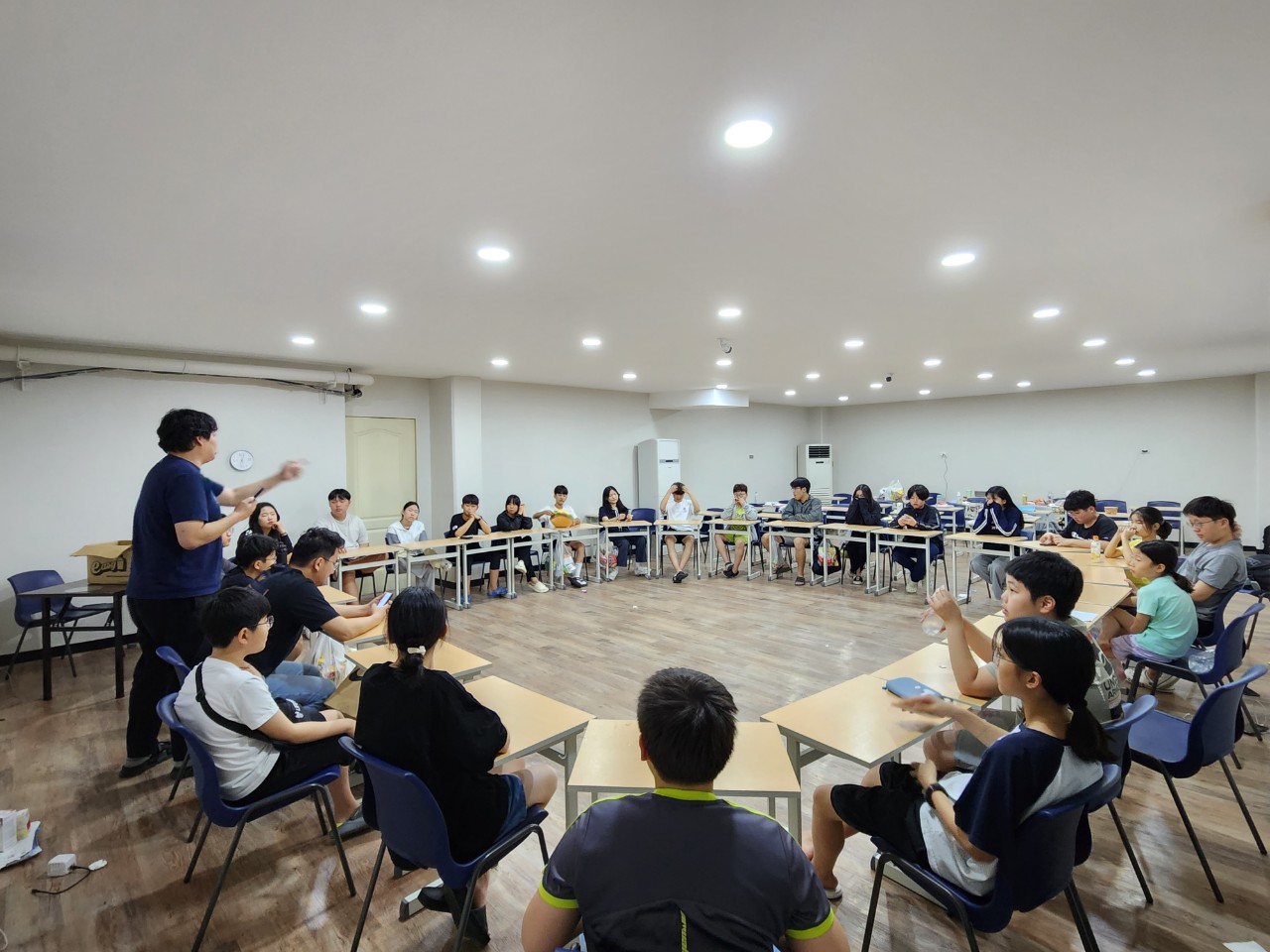 넓은 교실에서 서로를 바라보며 둘러앉은 학생과 강사