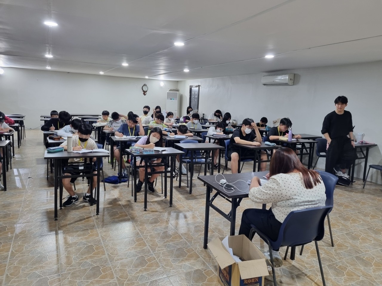 큰 교실의 책상에 앉아 학습하는 학생들