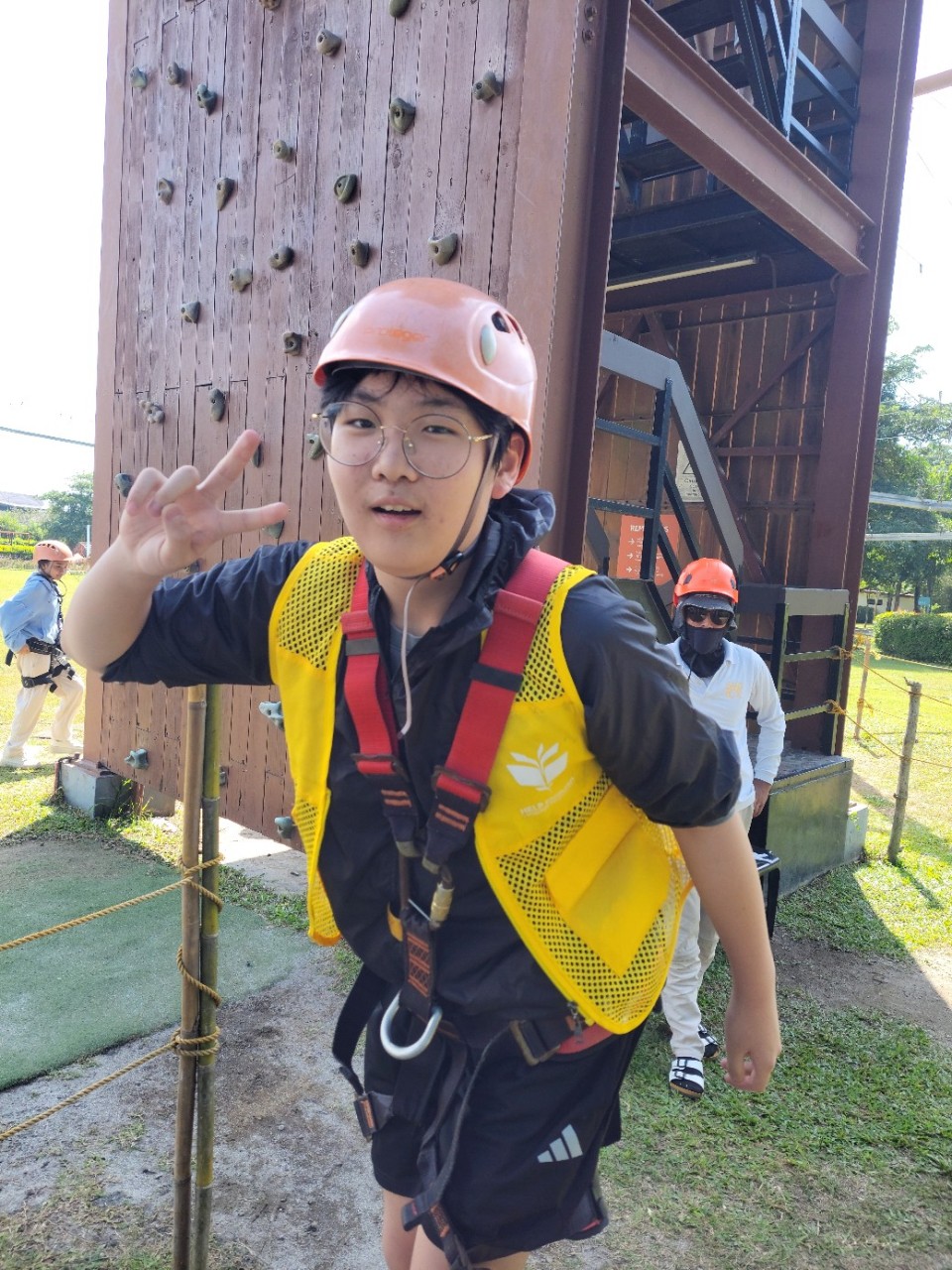 헬멧과 안전 장비를 착용하고 손으로 브이 표시를 하는 학생