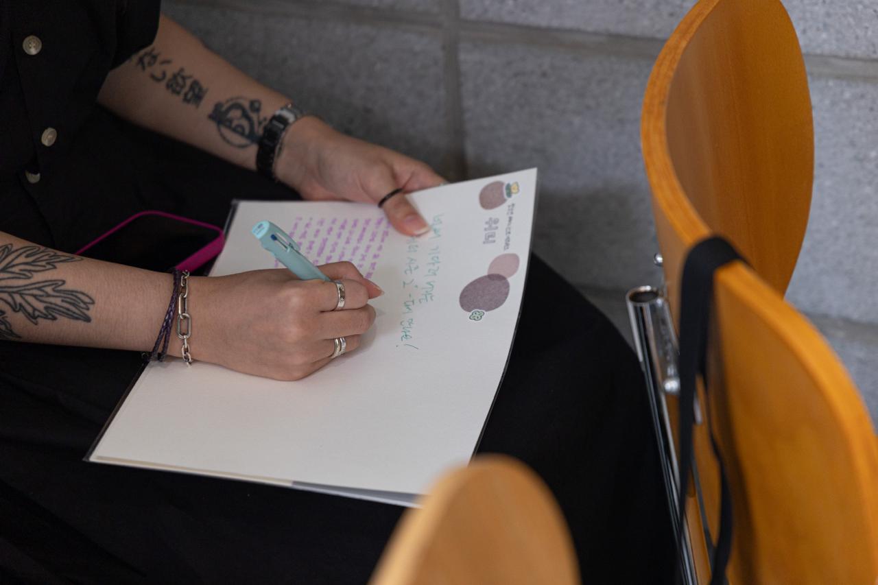 참가자가 위티에게 남길 말을 종이에 적고 있다. 
