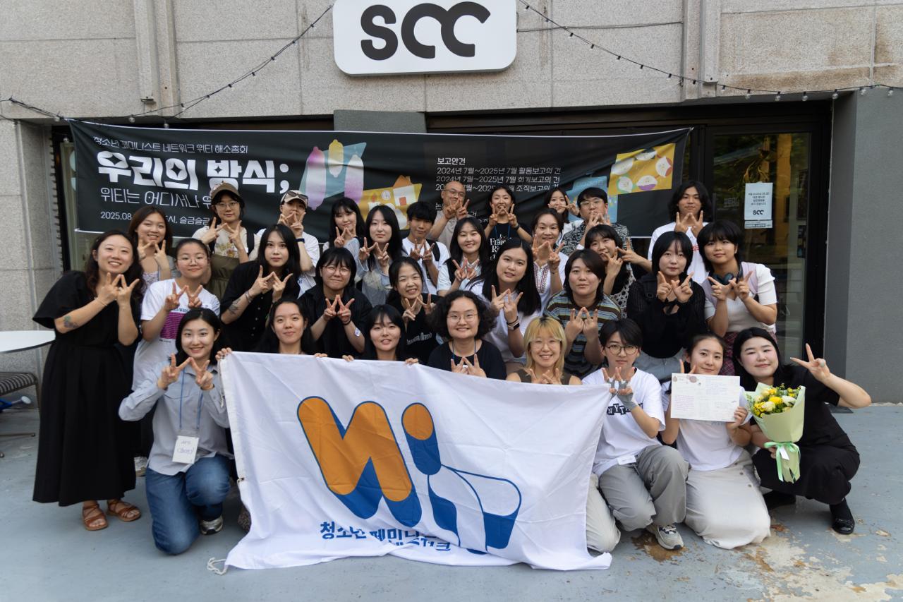 참가자들 모두가 위티의 깃발을 들고 찍은 단체 사진. 손가락으로 더블유를 만들고 있다. 