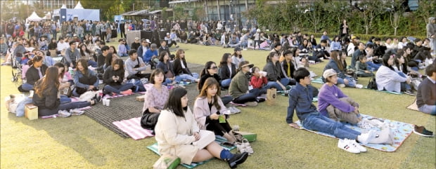‘청춘, 커피 페스티벌’에 참여한 시민들이 서울 롯데월드타워 잔디광장에서 공연을 보며 여유를 만끽하고 있다.(2019년 행사) 