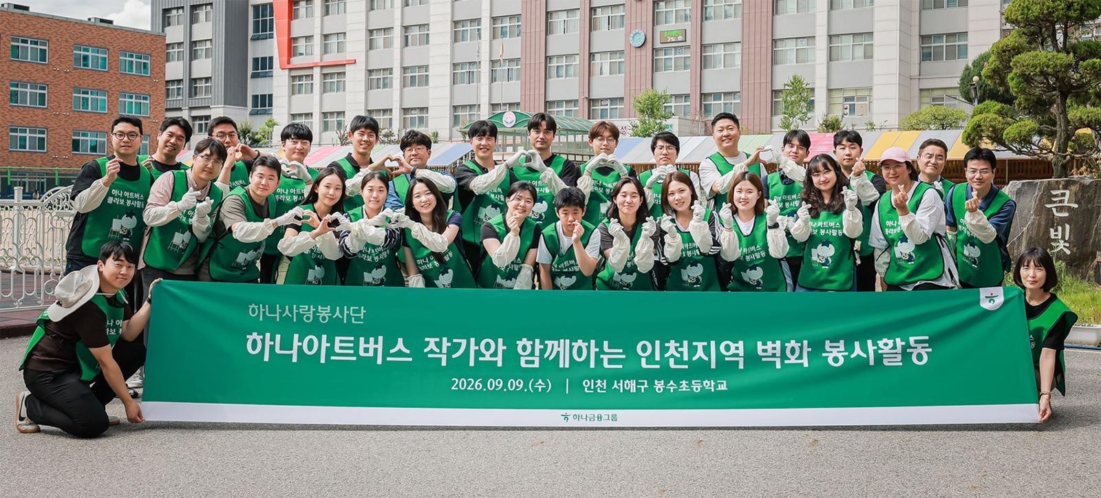 하나사랑봉사단 현수막 앞에서 손하트를 하며 단체 기념사진을 찍은 하나금융그룹 임직원들