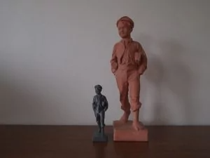 한 소년의 조각상과 이보다 작은 3D 프린터 모형물