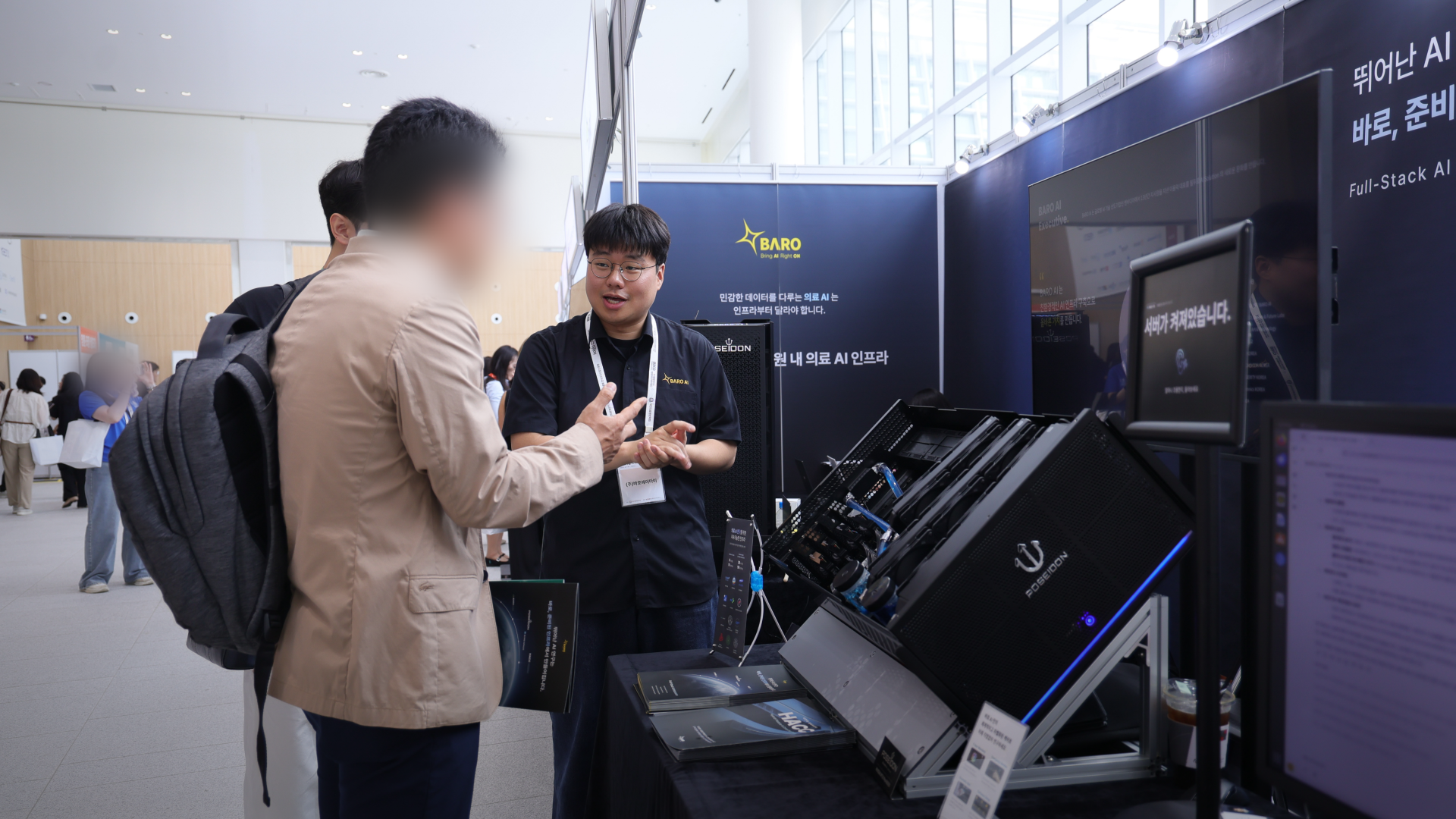 A2026 대한의료정보학회 춘계학술대회 바로AI(BARO AI) 부스에서 담당자가 방문객에게 POSEIDON 의료 AI 인프라와 Full-Stack AI 솔루션을 설명하는 장면을 담은 바로AI 테크 블로그 현장 사진입니다