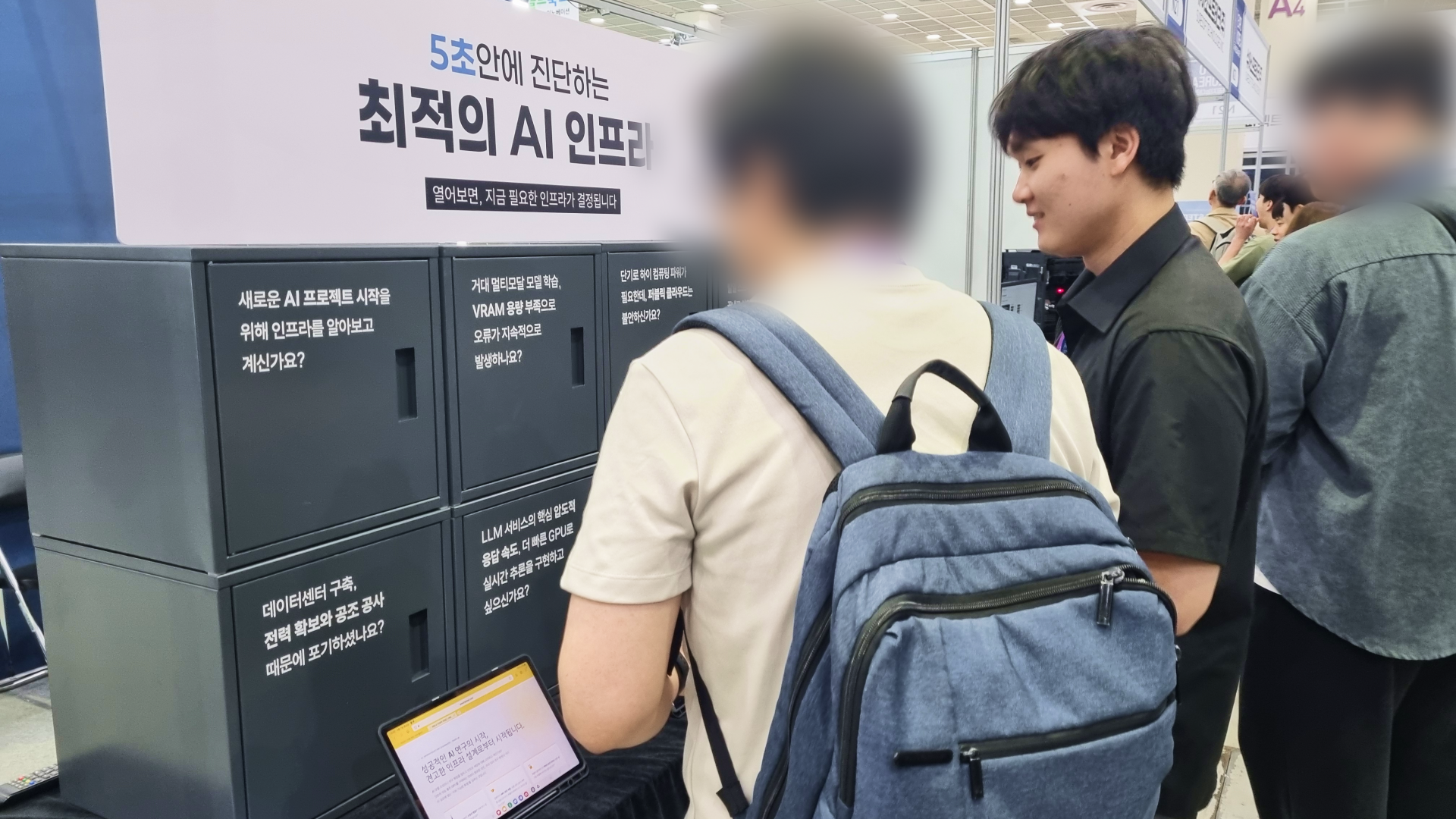 AI EXPO KOREA 2026 바로AI 부스 내 AI 인프라 5초 진단 코너에서 방문객이 서버 전력, 데이터센터 구축, GPU 성능 등 기업용 인프라 도입 과정의 실무적 고민이 적힌 캐비닛을 살펴보며 맞춤형 컨설팅을 받는 모습입니다
