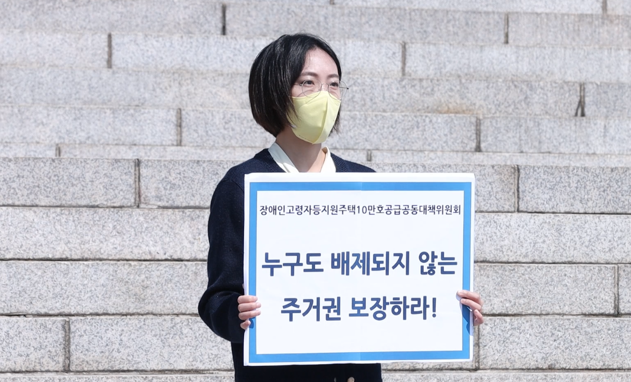 장혜영 의원이 "누구도 배제되지 않는 주거권 보장하라" 라고 쓰여있는 피켓을 들고 있는 사진. 사진을 누르면 장혜영 의원의 발언 동영상을 볼 수 있는 페이지로 이동합니다.