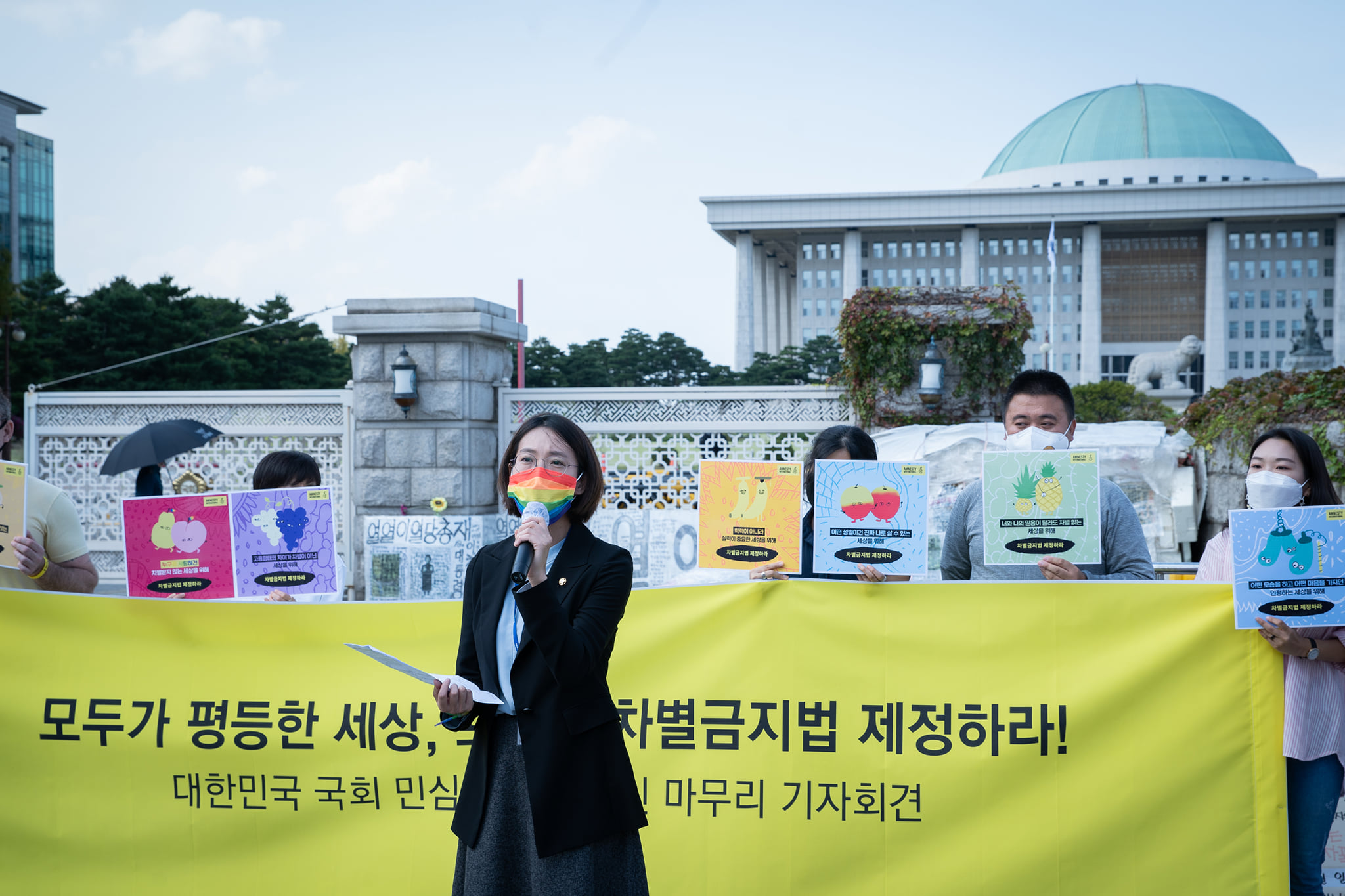 <사진> 장혜영 의원이 대한민국 국회 민심 전달 캠페인 마무리 기자회견에서 무지개색 마스크를 쓰고 발언하는 모습.