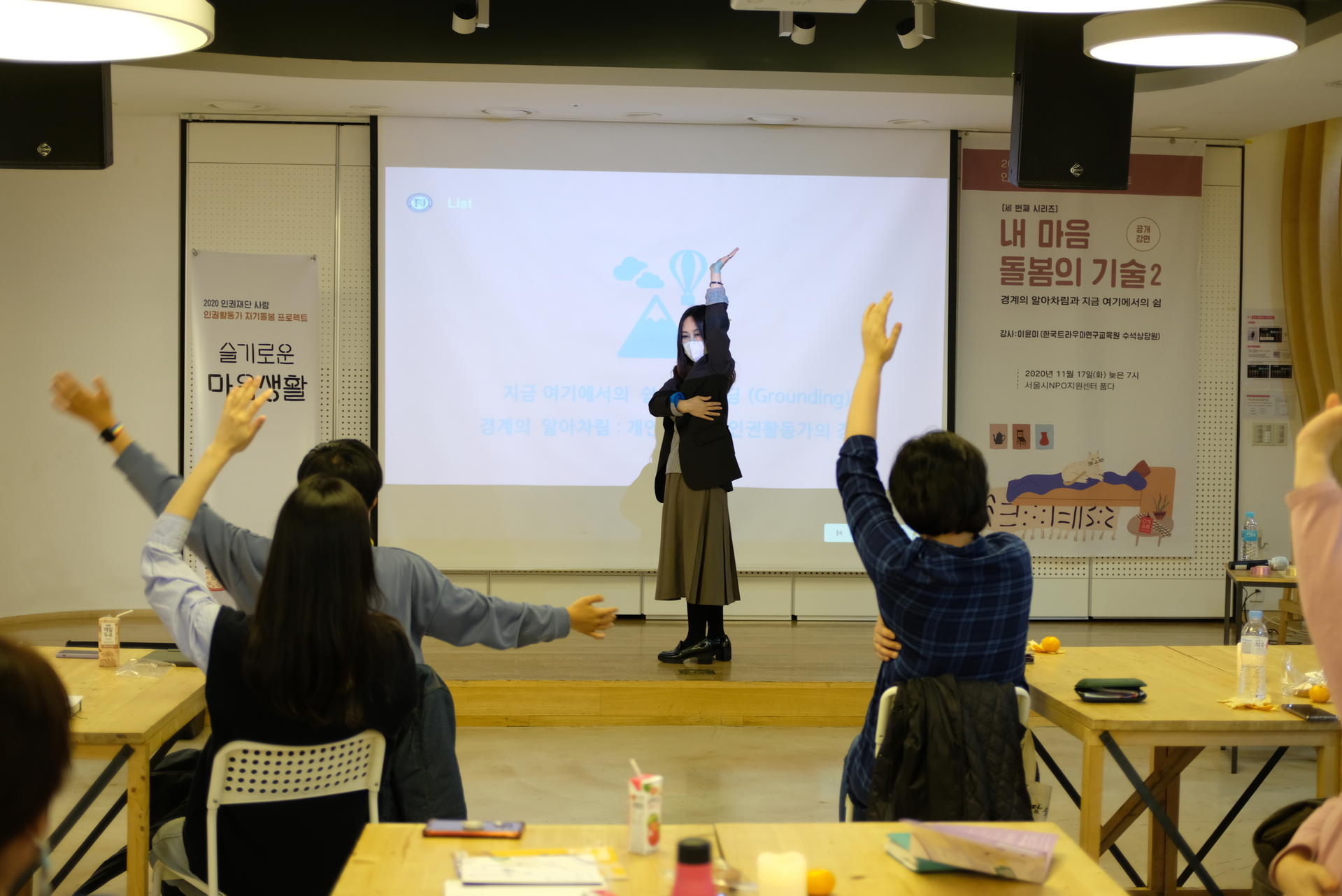 강사님이 앞에서 한쪽팔을 높이 들고 다른쪽팔로 몸통을 감싸고 있고, 참여자들은 따라하고 있음