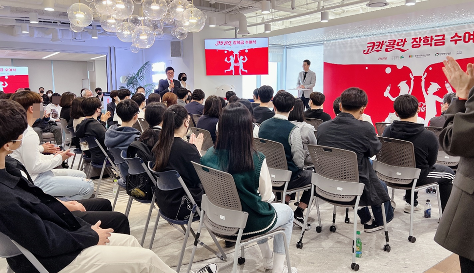 Many young students sit in rows of chairs during the Coca-Cola Scholarship Award Ceremony