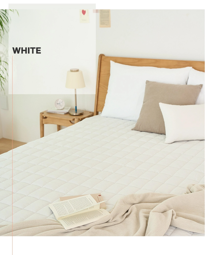 White Dr.Friend Sleep Pad arranged on a bed with pillows and a book, creating a clean and minimal sleep environment