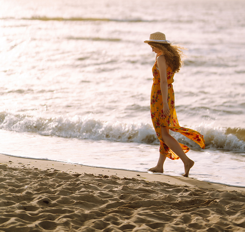 Person walking barefoot on the beach, symbolizing natural grounding and connection with the Earth"
