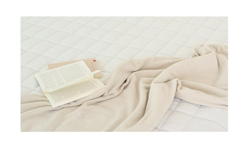 Close-up of a white Dr.Friend Sleep Pad with a blanket and an open book, emphasizing a calm and comfortable sleep setting