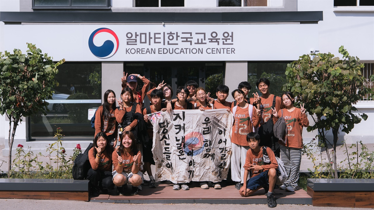 알마티한국교육원 앞에서 직접 만든 현수막을 들고
