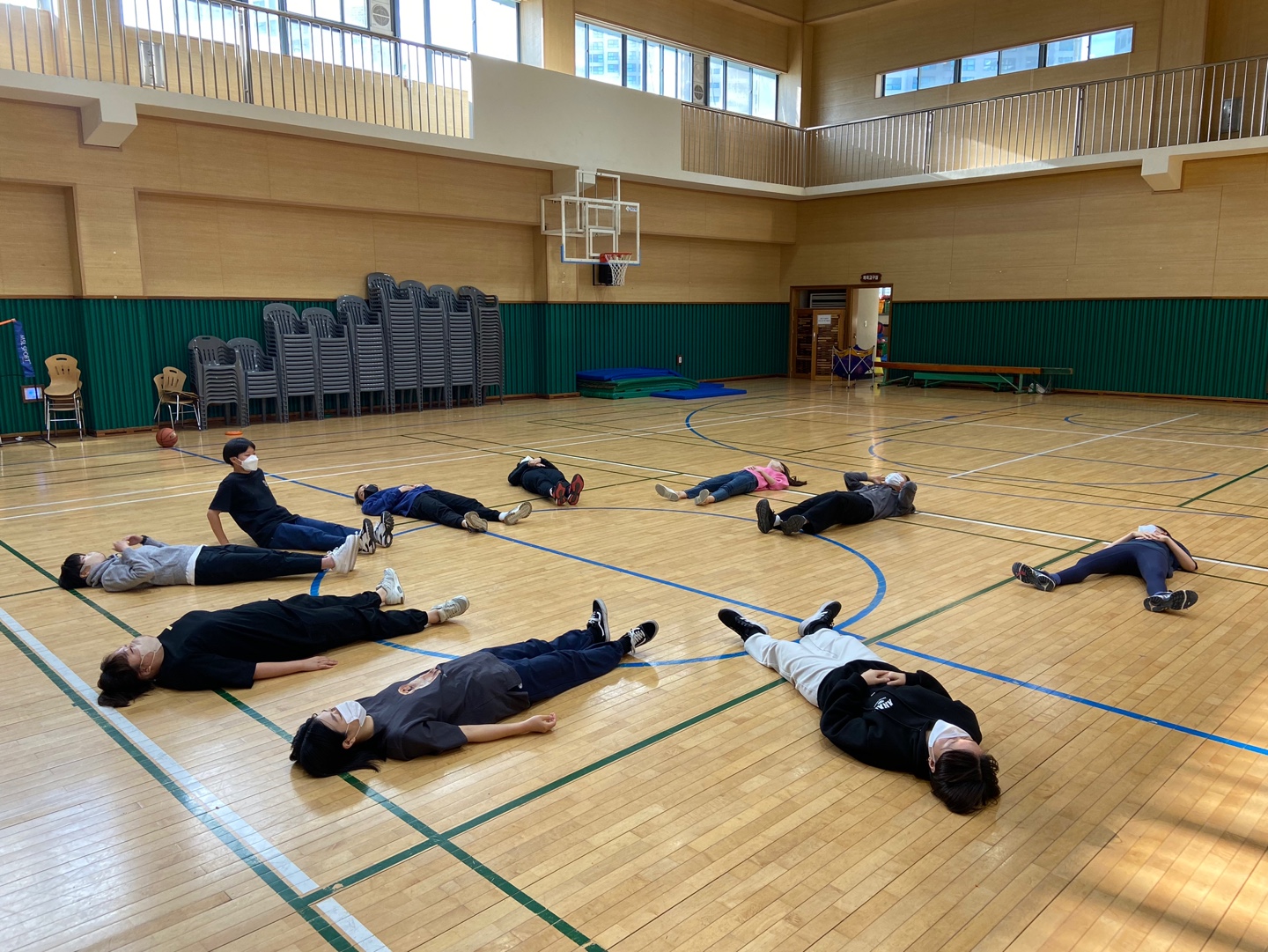 멤버들이 강당에 둥글게 누워있다. 