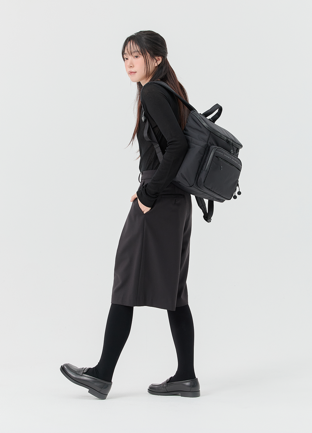 미니 백팩을 메고 걷는 모델의 측면 착용 모습으로 자연스러운 실루엣을 보여주는 컷