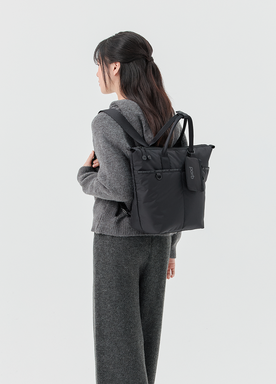 보르 투웨이 미니 백팩을 착용한 모델의 측면 뒷모습, 백팩 형태로 착용했을 때의 크기감과 어깨 스트랩 착용감을 보여주는 이미지