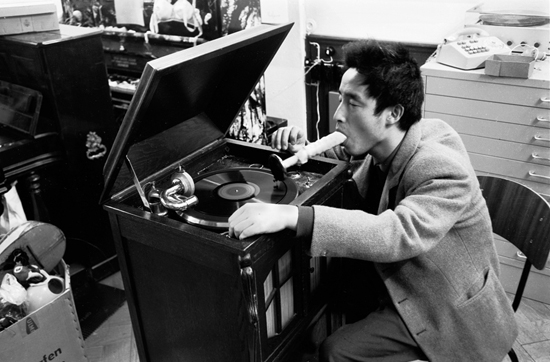 백남준, '음악의 전시 전자 텔레비전' 중 입으로 듣는 음악퍼포먼스, (1963) 사진 만프레드 몬트베. 위 작품은 모조페니스를 입에 물고 바늘을 레코드에 얹고 고막의 진동을 속귀로 전달받는 관객참여형 작품으로 성(性)을 소재한 점도 흥미롭다. ⓒ 백남준아트센터
