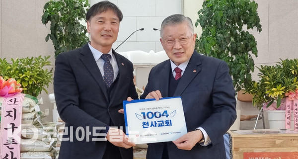 ▲지구촌사랑의쌀나눔재단 이사장 이선구 목사(오른쪽)가 남원1지부 장인철 지부장(왼쪽)에게 1004교회 현판을 전달하고 있다.