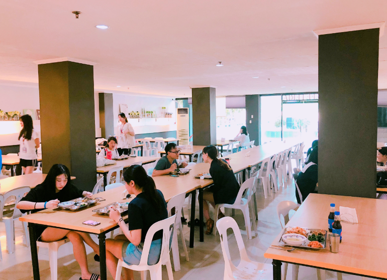 โรงอาหารกว้างขวางที่นักเรียนนั่งรับประทานอาหารที่โต๊ะ