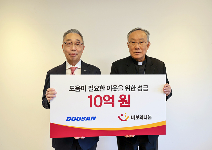 박지원 두산그룹 부회장(사진 왼쪽)과 구요비 재단법인 바보의 나눔 이사장이 3일 서울 명동성당에서 열린 성금 전달식에서 기념촬영을 하고 있다. 두산그룹
