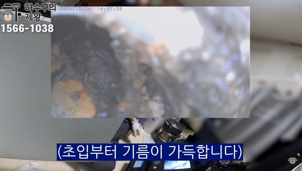 광진구 구의동 빌라 배관 내시경 점검 화면으로, 초입부부터 기름 슬러지가 두껍게 끼어 물길이 좁아진 상태를 보여주는 이미지