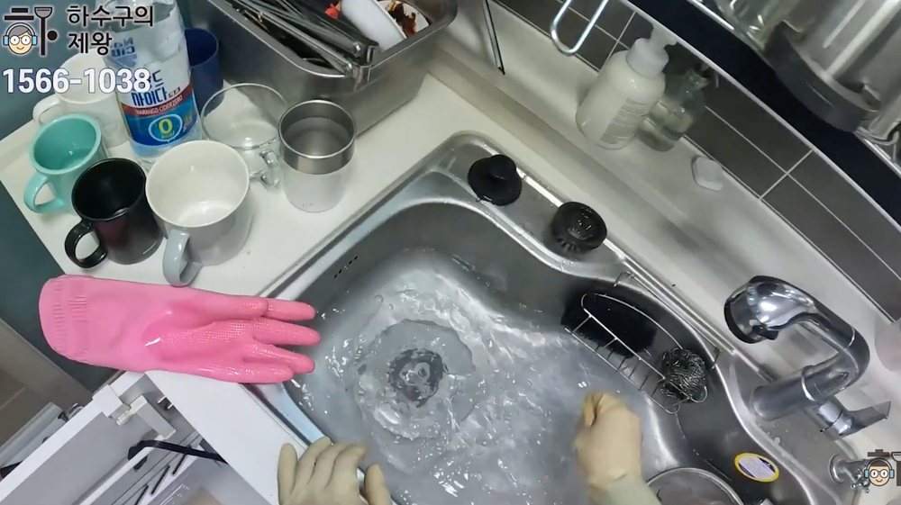 배관 청소 후 싱크대에 물을 가득 받아 한 번에 내려보내며 통수 상태를 확인하는 모습